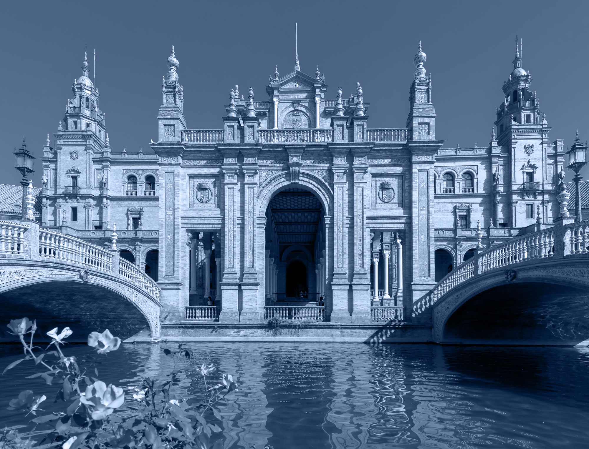 An ornate building with a bridge over a body of water in Seville, Spain.